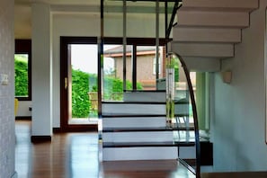 Una moderna scala con ringhiere in vetro che conduce a un'area esterna.