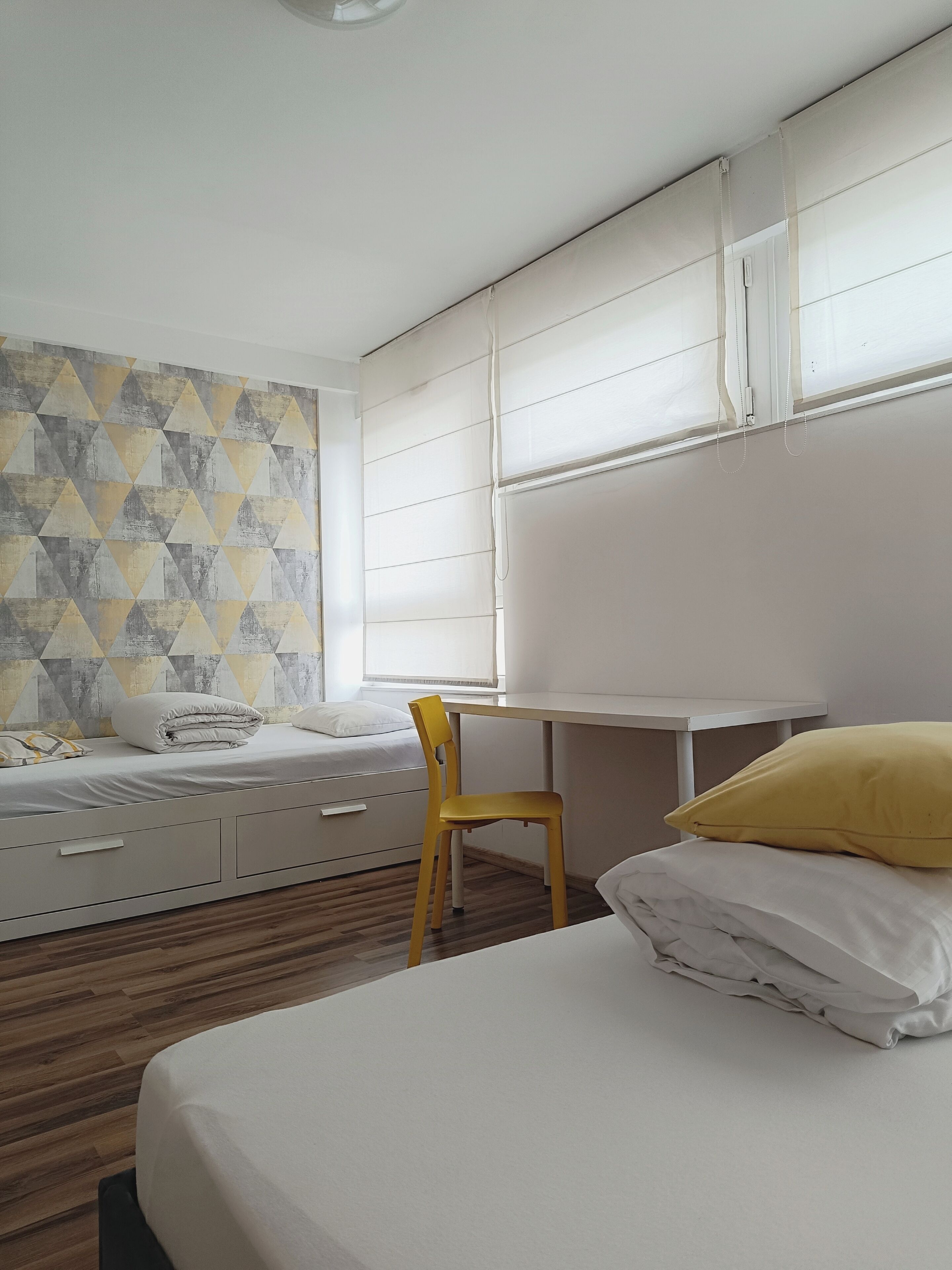 Une chambre à coucher avec un lit, un bureau, une chaise et une fenêtre.