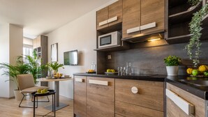 A modern kitchen with wooden cabinets, a built-in microwave, and a central island with a chair and fruit bowl. - Starter Apart Wrocław (Wroclaw)