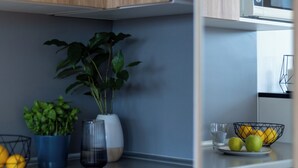 A modern kitchen with wooden cabinets, a microwave, and a bowl of lemons and apples on the counter. - Starter Apart Wrocław (Wroclaw)