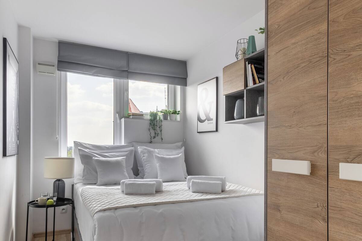 A modern bedroom with a bed, bedside table, and a wardrobe.