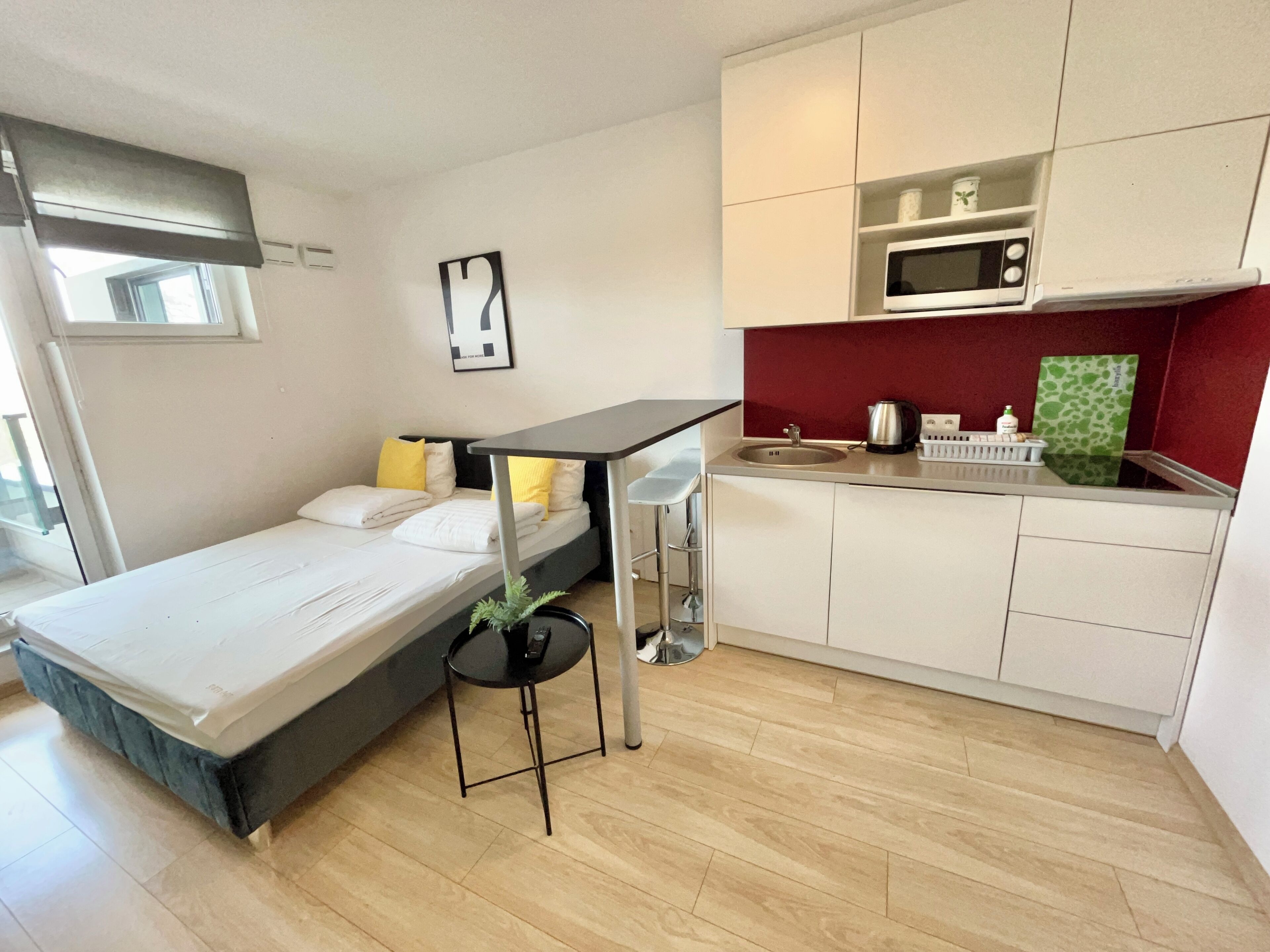 A compact room with a bed, a small table, a sink, and a microwave.