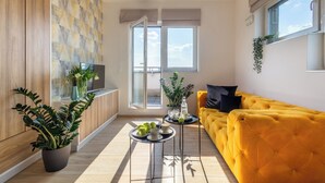 A modern living room with a yellow sofa, a coffee table, and a potted plant. - Starter Apart Wrocław (Wroclaw)