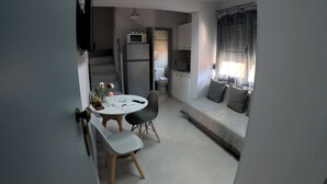 A compact living space with a kitchenette, a dining area with a round table and chairs, and a seating area with a sofa. - Data Maisonettes  (Chios)
