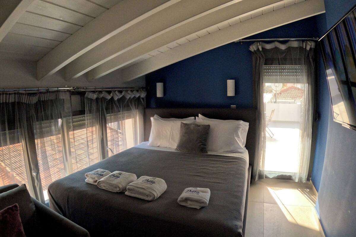A bedroom with a bed, curtains, and a view of the outside.