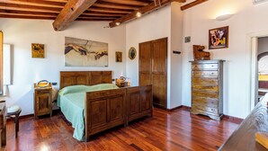 Ein Schlafzimmer mit einem hölzernen Bett, einer Kommode und einem Gemälde von sich entgegenstreckenden Händen.