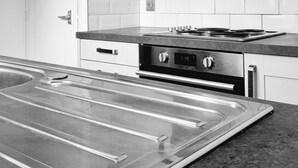 Une cuisine moderne avec des armoires blanches, une hotte en acier inoxydable et un plan de travail noir.