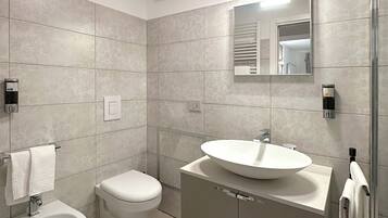 Un baño moderno con bidé, inodoro y lavamanos.