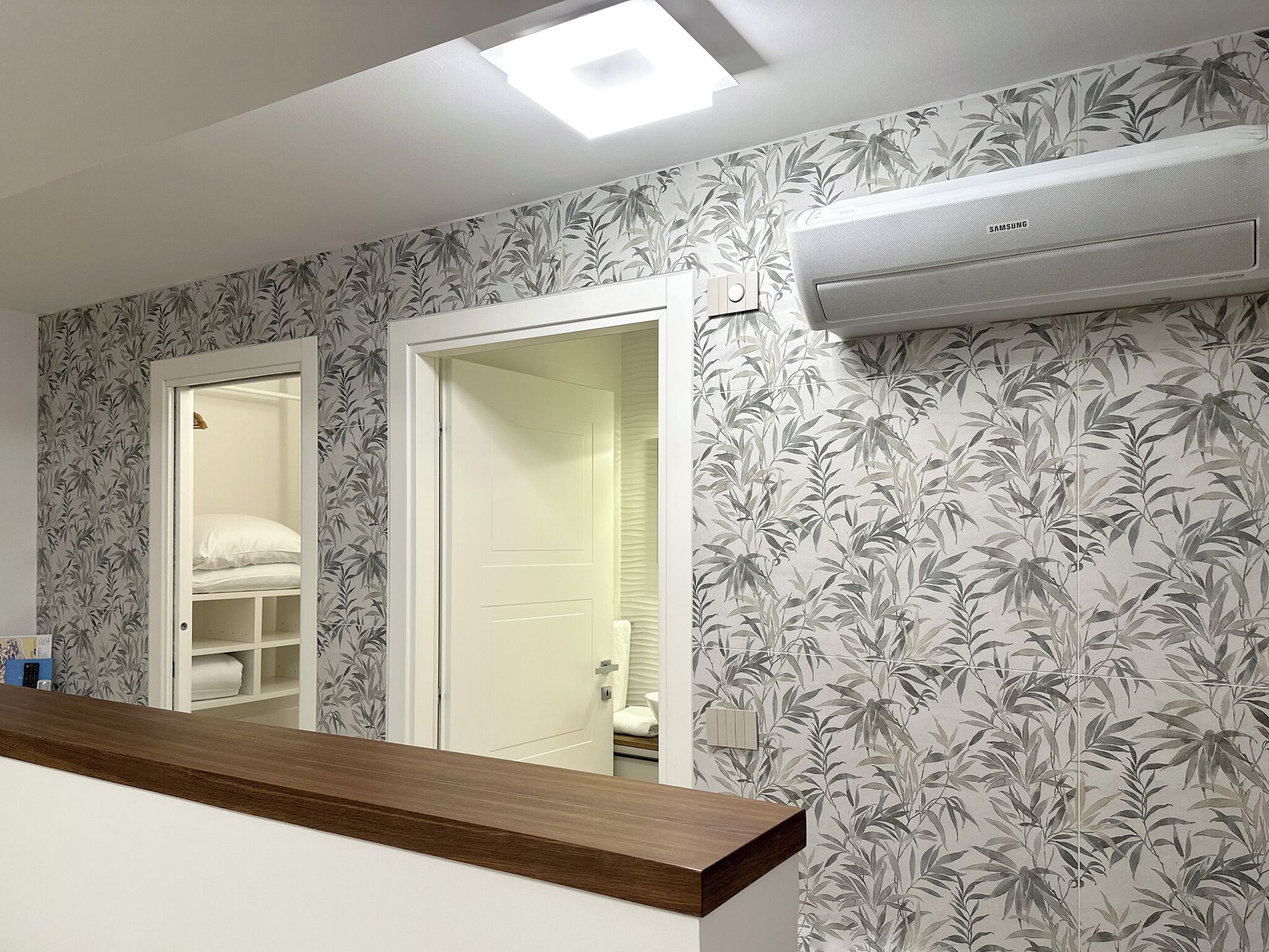 Een badkamer met toilet, douche en wastafel. Boven de wastafel hangt een spiegel en een witte deur leidt naar een andere kamer.
