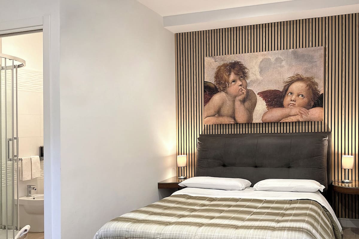 Um quarto com uma cama grande, uma cabeceira e um quadro com anjos na parede.
