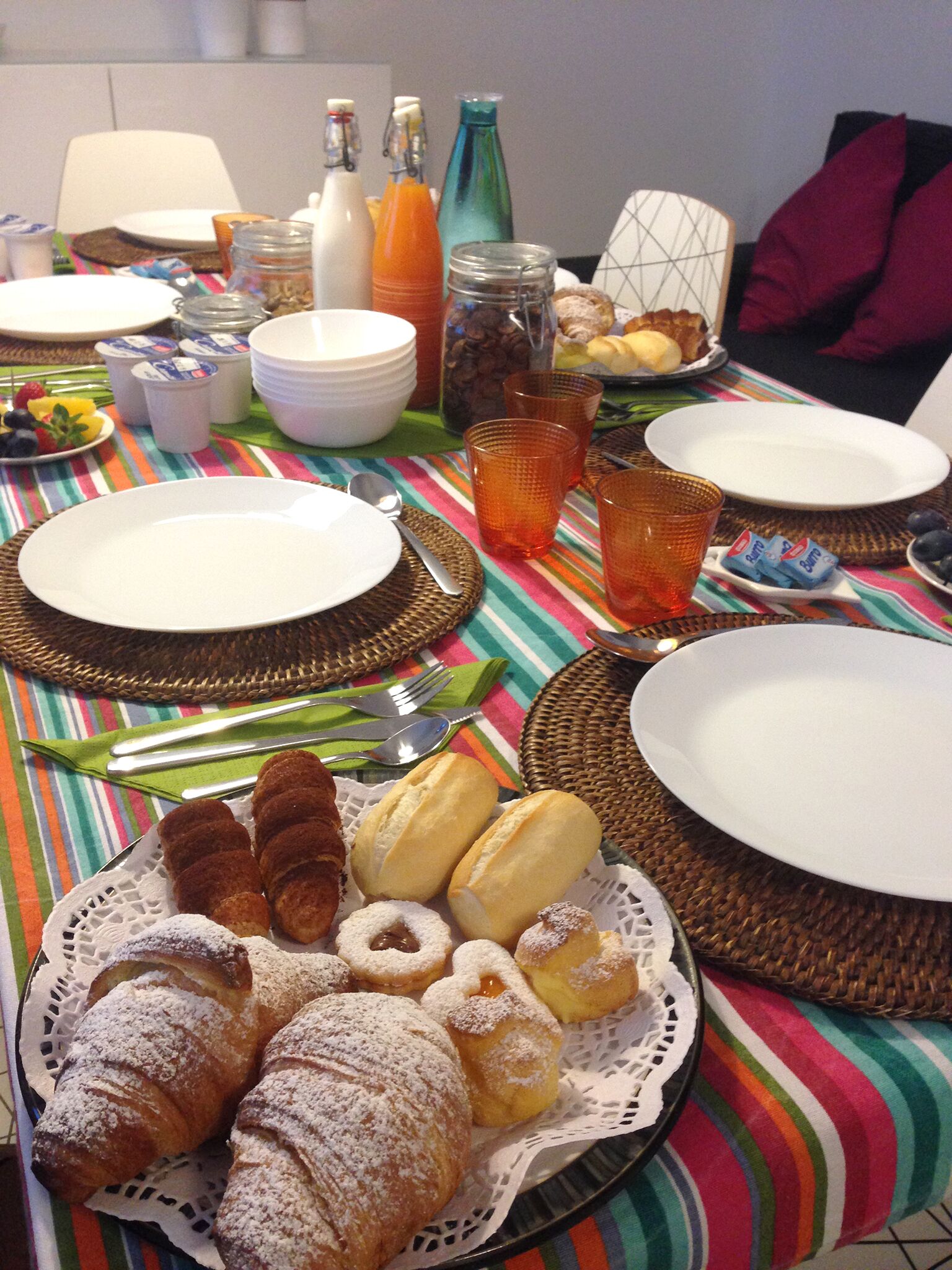 Een ontbijttafel met borden, bestek en diverse gebakjes.