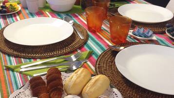 A breakfast table with plates, cutlery, and a variety of pastries.