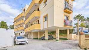 A multi-story residential building with balconies, a parking area, and a white car parked in front. - Apartment 'Burriana Beach Apt Nerja' with Mountain View, Wi-Fi and Air Conditioning (Nerja)