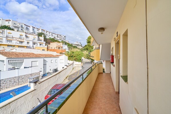 A balcony with a view of a swimming pool and adjacent buildings.