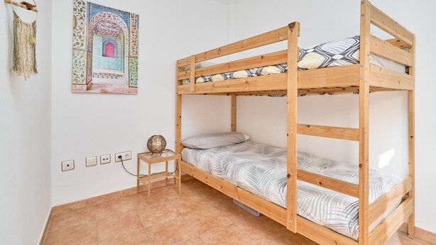 A bunk bed with a small bedside table and a wall-mounted lamp. - Apartment 'Burriana Beach Apt Nerja' with Mountain View, Wi-Fi and Air Conditioning (Nerja)