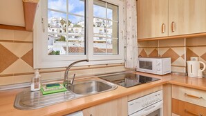 A kitchen with a window, a sink, a microwave, a kettle, and a dishwasher. - Apartment 'Burriana Beach Apt Nerja' with Mountain View, Wi-Fi and Air Conditioning (Nerja)