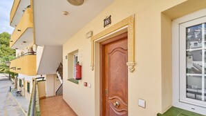 A hotel entrance with a wooden door, a fire extinguisher, and a window with a view of buildings. - Apartment 'Burriana Beach Apt Nerja' with Mountain View, Wi-Fi and Air Conditioning (Nerja)