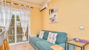 A room with a teal sofa, a glass table with a puzzle box, and a window with a curtain. - Apartment 'Burriana Beach Apt Nerja' with Mountain View, Wi-Fi and Air Conditioning (Nerja)