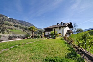 Une maison avec un jardin, un chemin et une vue sur les collines environnantes.