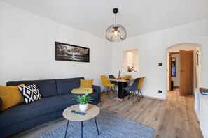 Un salon moderne comprenant un canapé, un coin repas et un couloir menant à une porte.