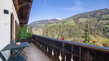 Un balcon avec une table et des chaises, donnant sur un paysage montagneux.