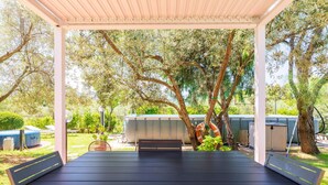 An outdoor patio with a black table and chairs, surrounded by trees and a covered area. - Apartment 'Santina' with Mountain View, Wi-Fi and Air Conditioning (Girasole)