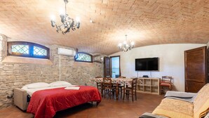 A cozy room with a bed, a dining table, chairs, a TV, and a fireplace. - Apartment 'Santina' with Mountain View, Wi-Fi and Air Conditioning (Girasole)