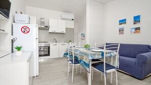 Une cuisine compacte avec des meubles blancs, une cuisinière et un coin repas comprenant une table et des chaises.