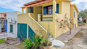 Un bâtiment jaune avec un toit rouge, un escalier et une porte verte.
