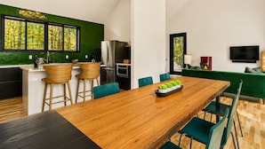 A modern kitchen with a dining area, a TV, and a fireplace. - Scandinavian Chalet | Games | Hot Tub/Sauna (Dansville)