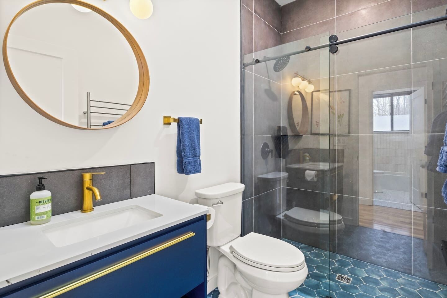 Un bagno moderno con doccia vetrata, un water bianco e un mobile lavabo con rubinetto dorato.