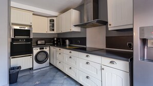 Una cocina compacta con electrodomésticos integrados, lavadora y extractor de acero inoxidable.