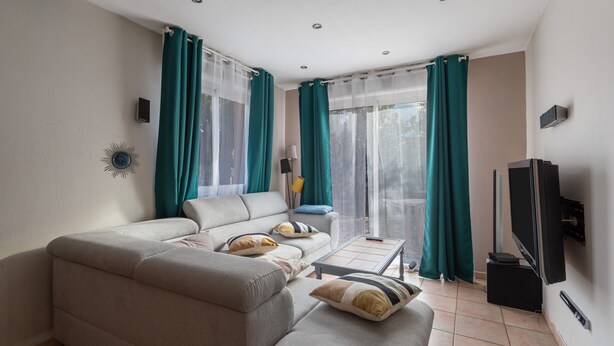 Una sala de estar con sofá, mesa de centro, televisor y cortinas.