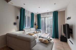Ein Wohnzimmer mit einer Couch, einem Couchtisch, einem Fernseher und Vorhängen.