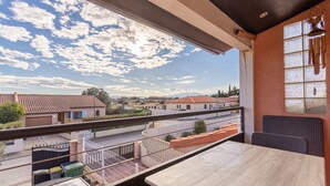 Un balcón con vistas a casas y un cielo despejado.