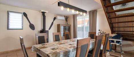 Un coin repas avec une table recouverte d’une nappe à motifs, entourée de chaises en bois dotées d’assises rembourrées.