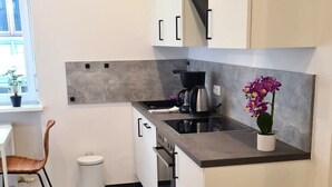 A modern kitchen with white cabinets, a grey countertop, and a small potted orchid. - Apartment Ilz - in the center, parking, kitchen, quiet location (Passau)