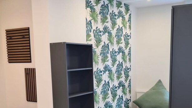 A compact bedroom with a bed, a small desk, and a shelving unit. - Apartment Ilz - in the center, parking, kitchen, quiet location (Passau)