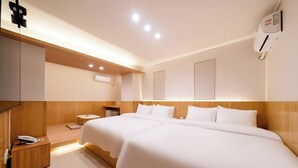 Habitación de hotel con dos camas, cabecero de madera, mesita de noche con teléfono y aire acondicionado de pared.