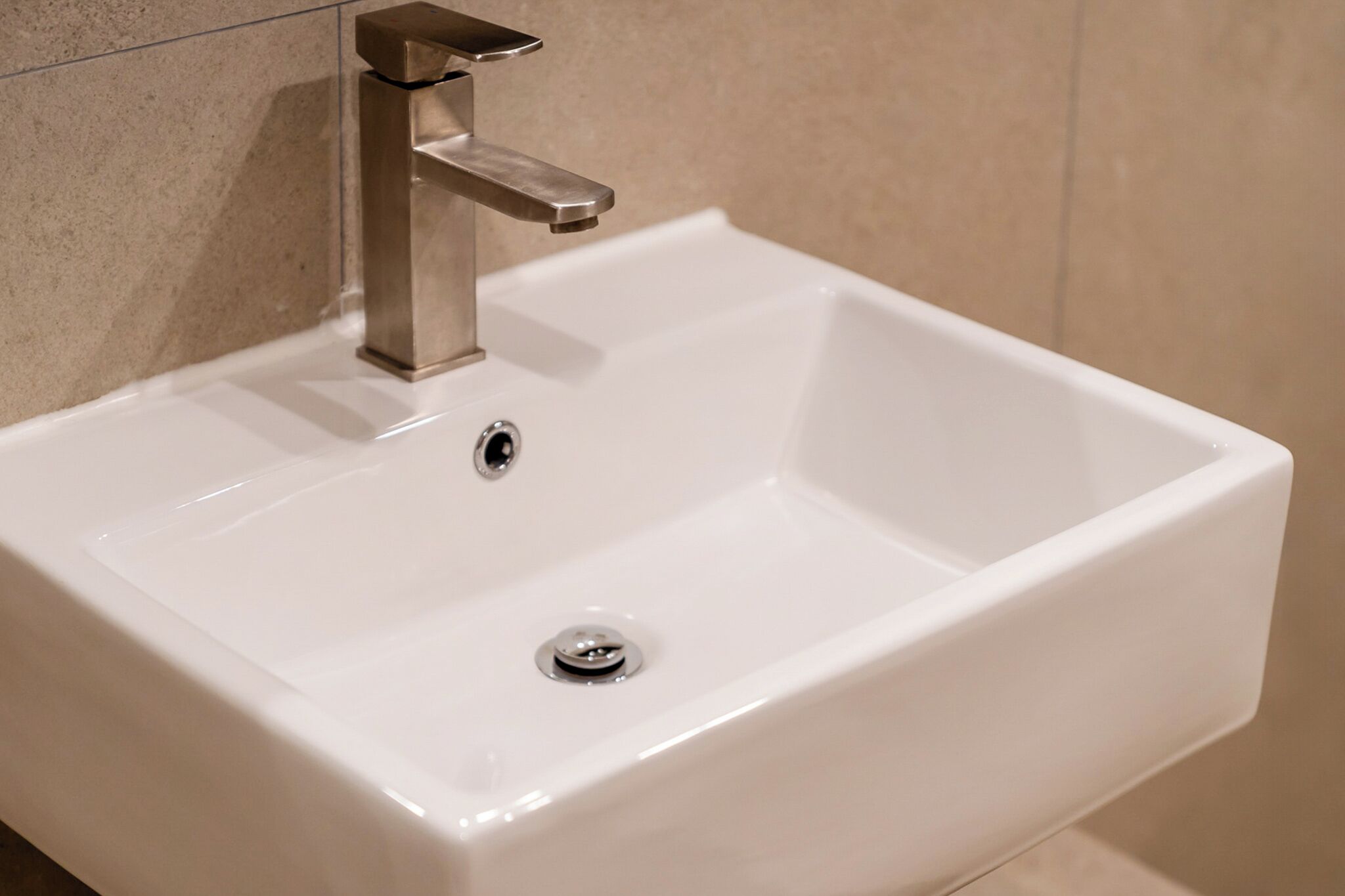 A white bathroom sink with a modern faucet and two drains.
