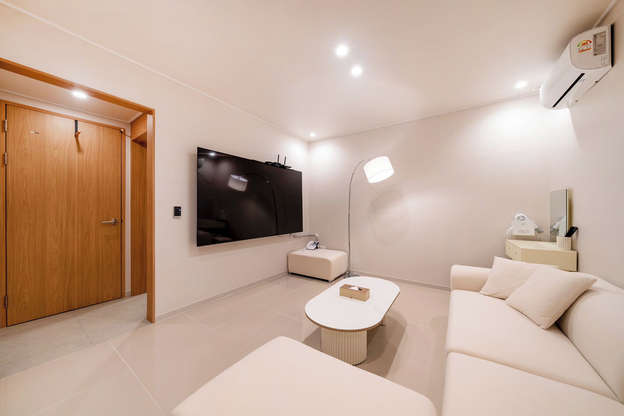 A modern living room with a flat-screen TV, a sofa, a coffee table, and a wooden wardrobe.
