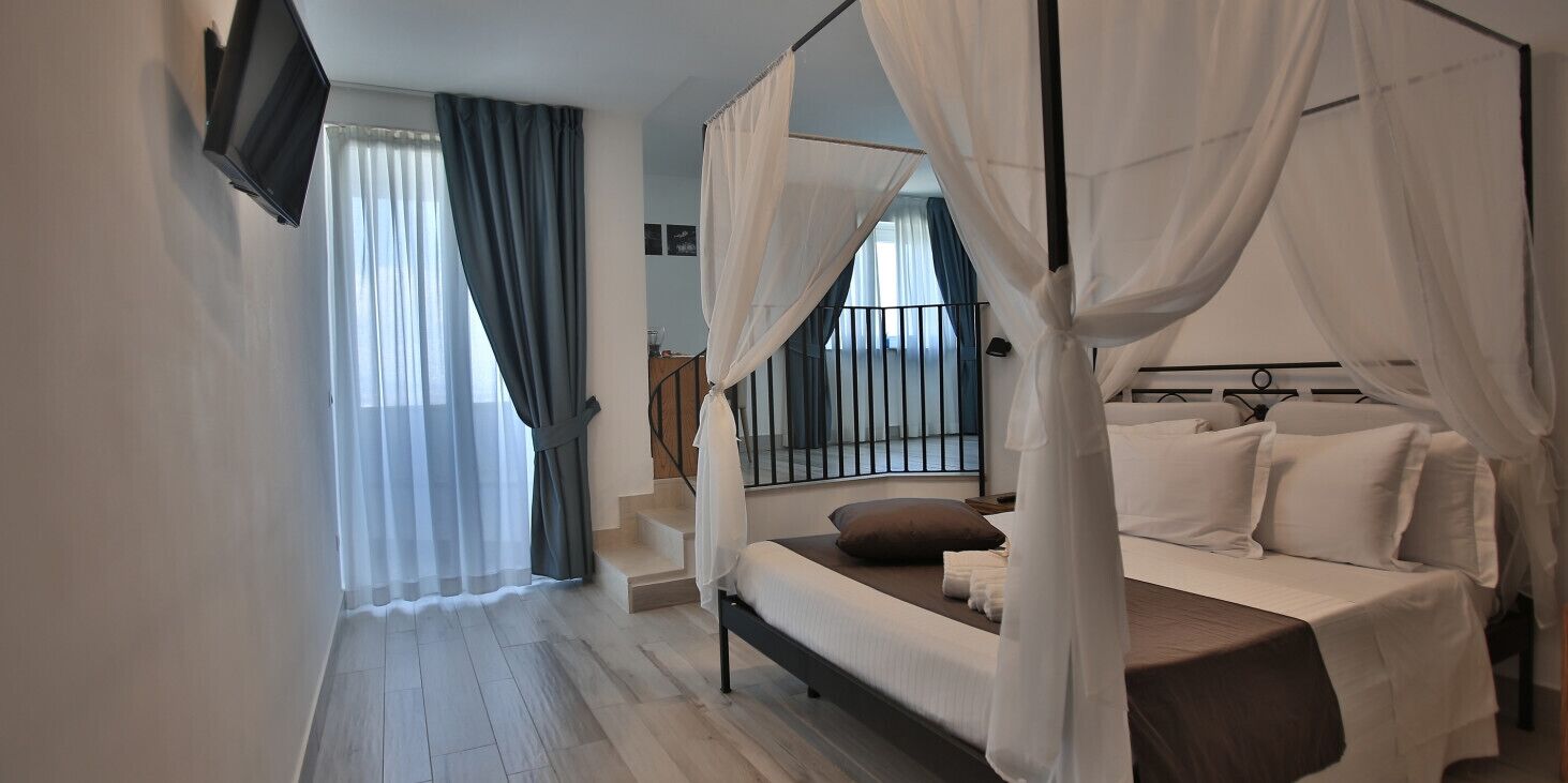 A bedroom with a bed, a TV, a staircase, and a balcony.