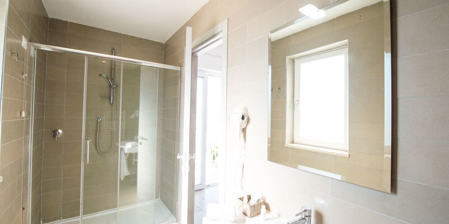Une salle de bain moderne avec une douche à parois de verre, un grand miroir et des toilettes.