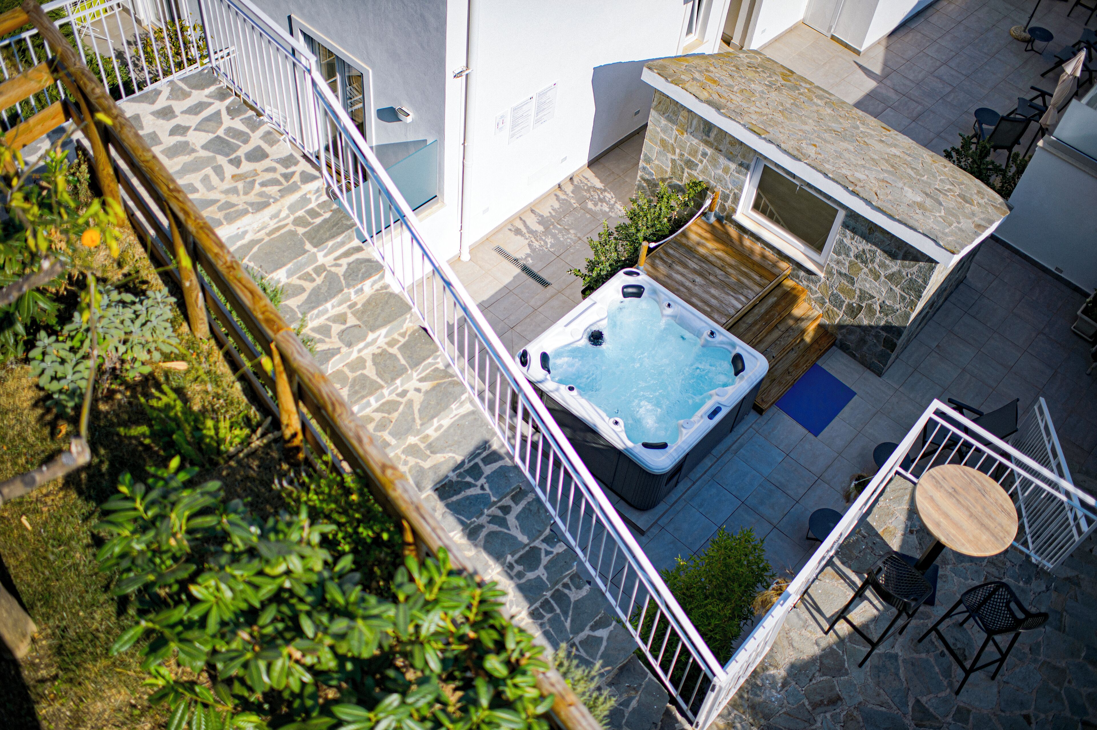 Un patio empedrado con jacuzzi, asientos exteriores y un muro de piedra.