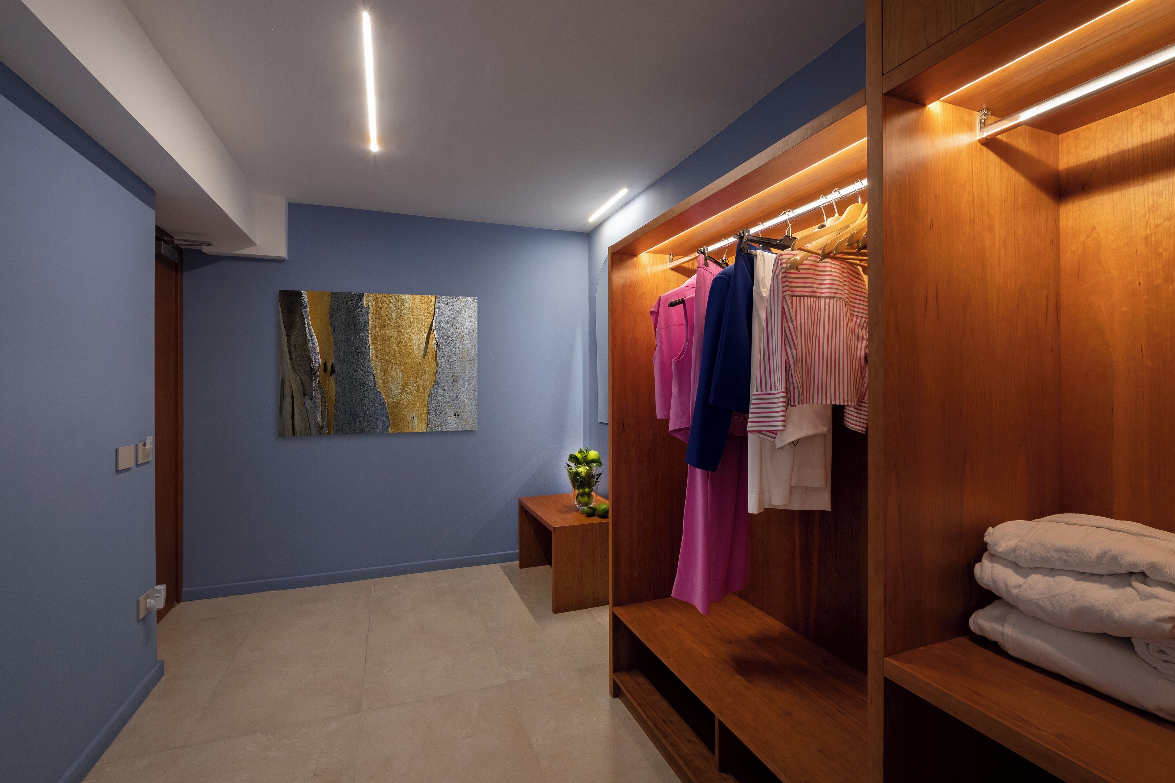 A modern bathroom with a wooden vanity, a towel rack, and a painting on the wall.
