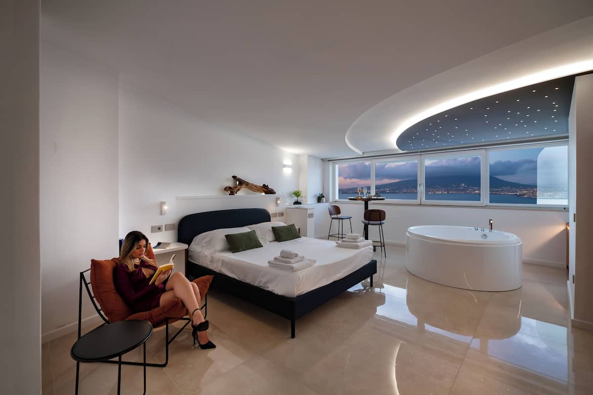 Un dormitorio moderno con una cama grande, una bañera y vistas a la ciudad.
