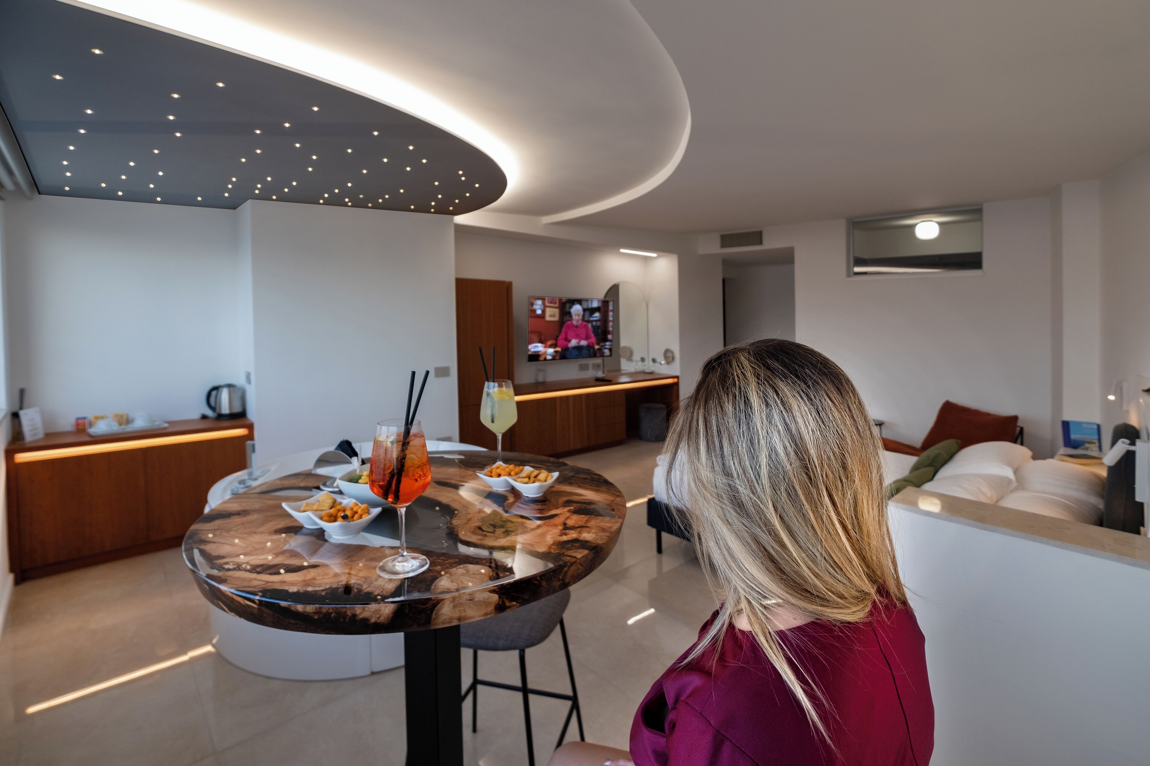 Uma sala de estar moderna com uma mesa de jantar redonda, um sofá e uma televisão ao fundo.