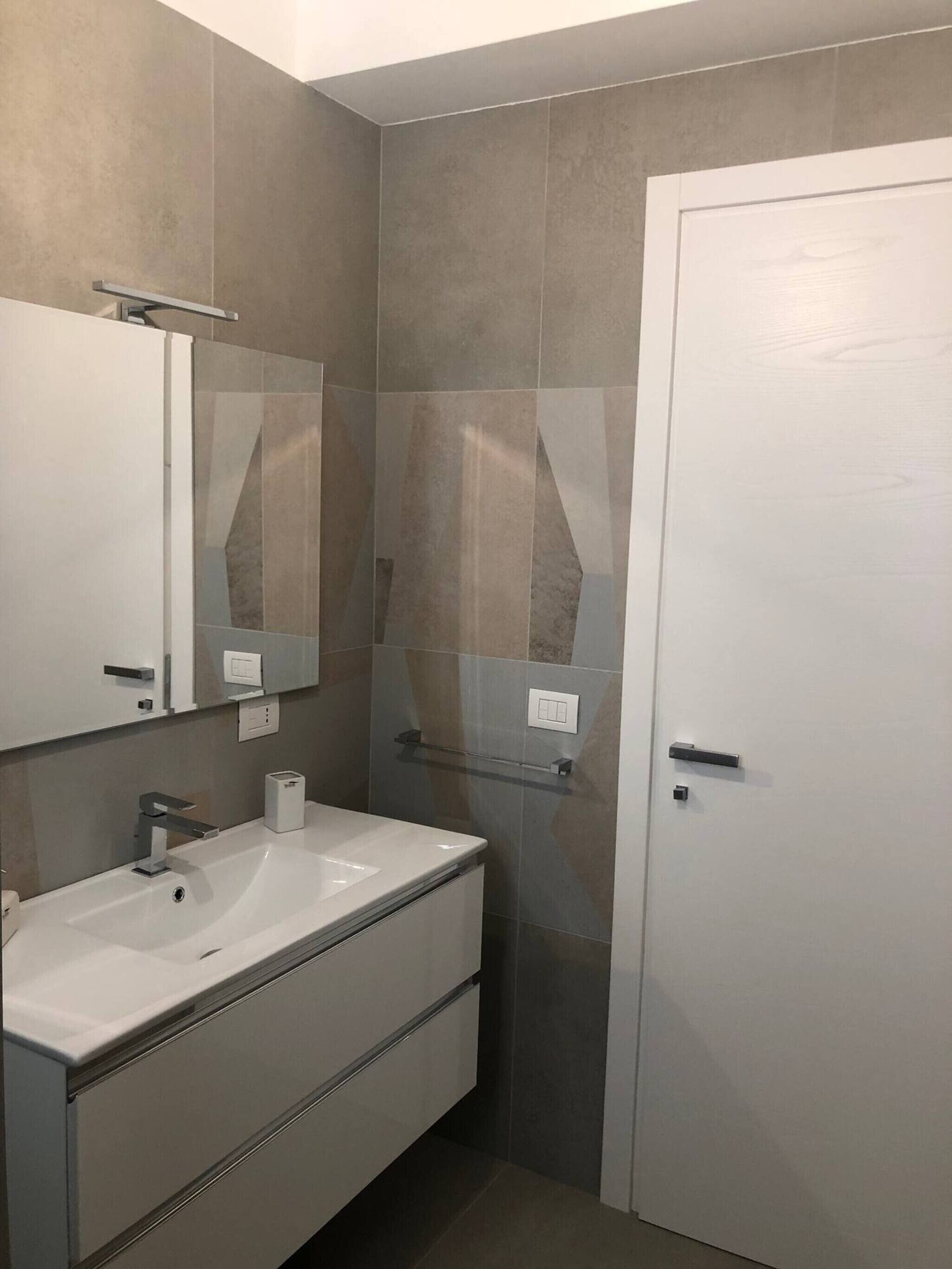 Une salle de bain avec un lavabo blanc, un miroir et un porte-serviettes.