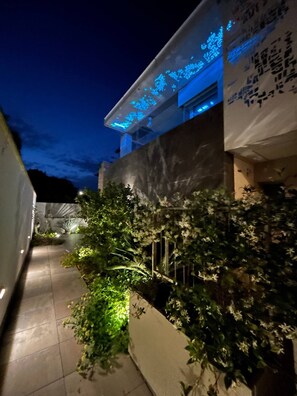 Un chemin menant à un bâtiment dont la partie supérieure est illuminée en bleu et sur lequel est affichée une banderole avec du texte.