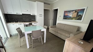 Un espacio habitable compacto con kitchenette, comedor, sofá y mueble para TV.